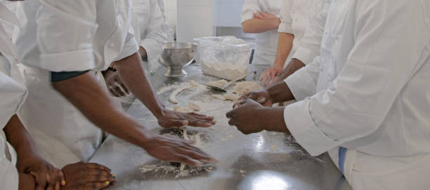 istock Close-up hands forming dough balls for baking pancakes on metal table during manufacturing. 1496148432