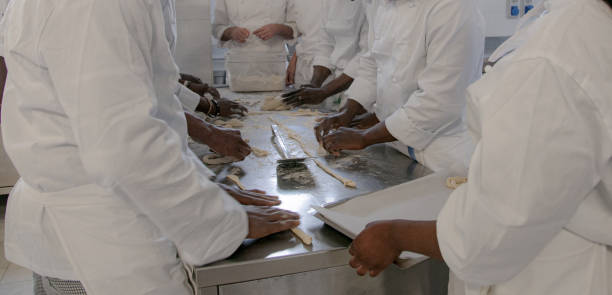 istock Close-up hands forming dough balls for baking pancakes on metal table during manufacturing. 1496148434