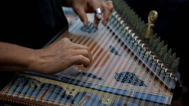 close up of the man playing the qanun