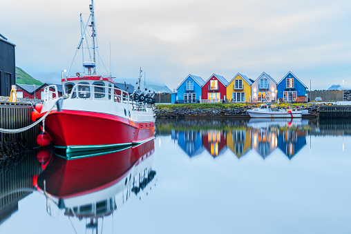 Reflections of colourful houses and boats in the water of a bay, dusk time, Leirvik, Eysturoy Island, Faroe Islands