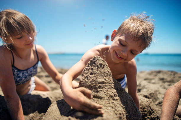 istock Three kids building sandcastles on the beach 1496152519