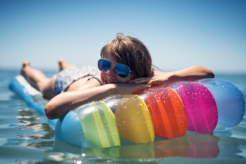 Girl relaxing on a colorful pool raft enjoying beach and sea vacations\nNikon D810