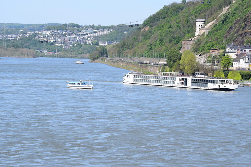 Koblenz, Germany - 05/03/2023: A Big Cruise Ship While Turning on the Rhine with the tiny remaining Ferry in Koblenz