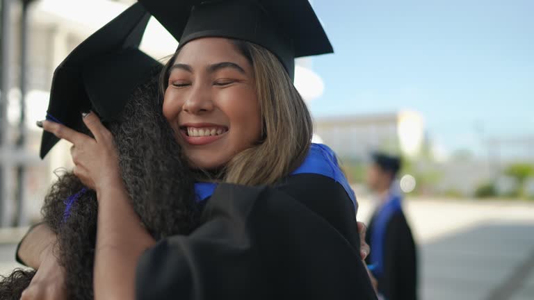 Young graduate woman embracing her friend on graduation