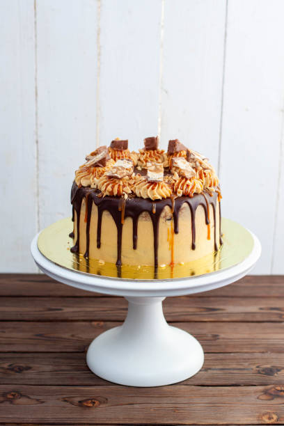 Gorgeous snickers cake with peanut butter cream, melted chocolate, candy bars and salted caramel