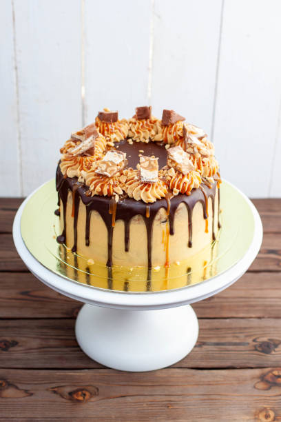Gorgeous snickers cake with peanut butter cream, melted chocolate, candy bars and salted caramel