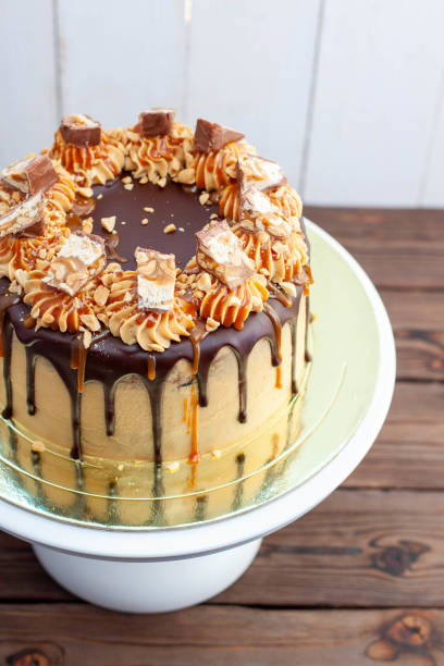 Gorgeous snickers cake with peanut butter cream, melted chocolate, candy bars and salted caramel