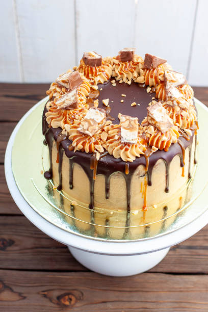 Gorgeous snickers cake with peanut butter cream, melted chocolate, candy bars and salted caramel
