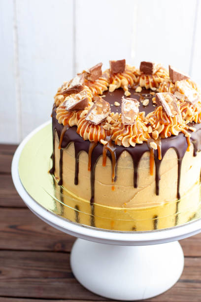 Gorgeous snickers cake with peanut butter cream, melted chocolate, candy bars and salted caramel