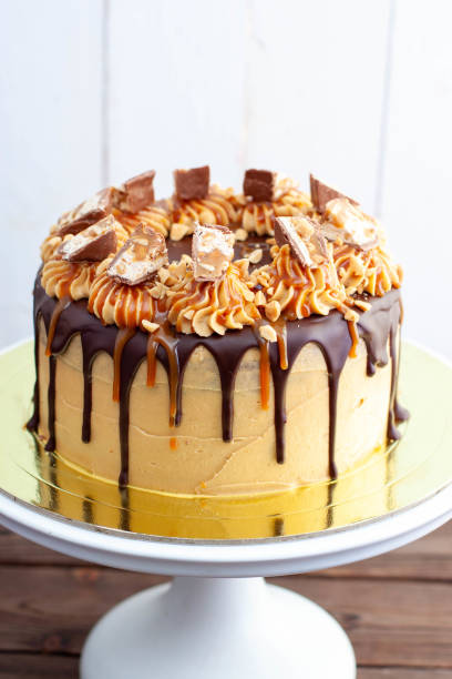 Gorgeous snickers cake with peanut butter cream, melted chocolate, candy bars and salted caramel