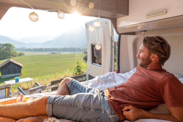 istock Man lying at the back of a van looking at the mountains 1496158687