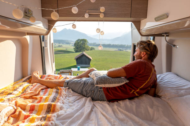 istock Man lying at the back of a van looking at the mountains 1496158705
