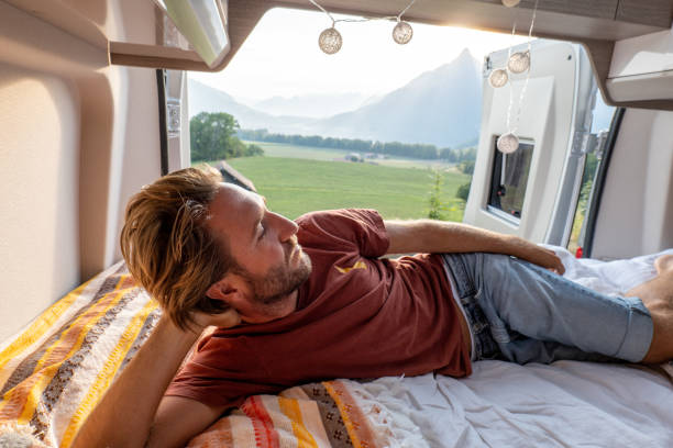 istock Man lying at the back of a van looking at the mountains 1496158741