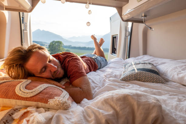 istock Man lying at the back of a van looking at the mountains 1496158773
