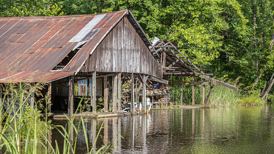 An old fishhouse along a freshwater river can is a picturesque sight, evoking a sense of nostalgia and a connection to nature. The fishhouse is weathered and worn, with a rustic charm that suggests it has been standing for many years.\n\nAs you approach the fishhouse, you notice the smell of the river and the sound of the water flowing nearby. The structure is built on stilts or on the riverbank itself, with a wooden deck extending out over the water.\n\nThe fishhouse is made of wood, with a simple design that reflects its practical purpose. There are windows that can be opened to let in the breeze, and small porch with a rocking chair where a fisherman can sit and watch the river flow by.\n\nOverall, an old fishhouse along a freshwater river brings serene and peaceful place, offering a glimpse into a simpler time and a connection to the natural world.