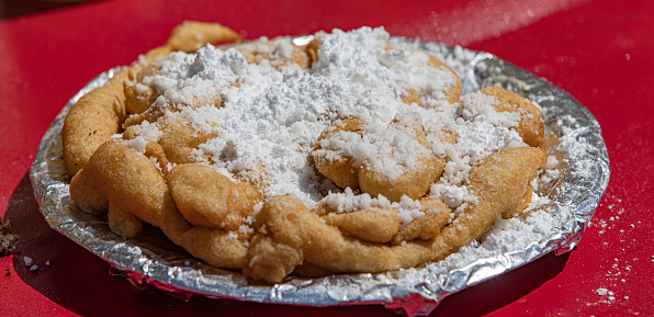 Funnel cake is a popular deep-fried dessert that is commonly found at fairs, carnivals, and theme parks. It is made by pouring a batter made of flour, eggs, milk, sugar, and baking powder through a funnel into hot oil, creating a spiral or lattice pattern. The batter is then fried until crispy and golden brown.

After the funnel cake is fried, it is typically dusted with powdered sugar and served hot. Some variations of funnel cake may include additional toppings such as whipped cream, fruit, chocolate sauce, or caramel sauce.

Funnel cakes have a sweet, crispy exterior with a soft, doughy interior. They are often enjoyed as a treat or snack, and can be shared with friends or family. In addition to being a popular dessert at fairs and carnivals, funnel cakes can also be made at home using a funnel or a plastic squeeze bottle to create the spiral pattern.