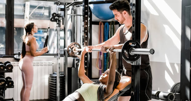 istock Muscular instructor helping sportswoman with barbell 1496161305