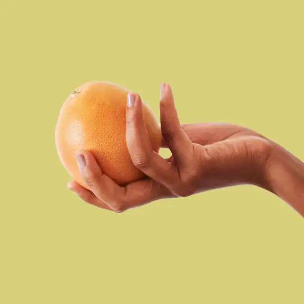 Photo of Hands, orange and fruit for vitamin C, healthy diet plan or nutrition against a studio background. Hand holding fruity food, nectarine or grapefruit for health, organic wellness or citrus on mockup