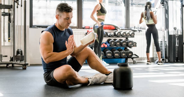 Strong man making protein cocktail in gym stock photo