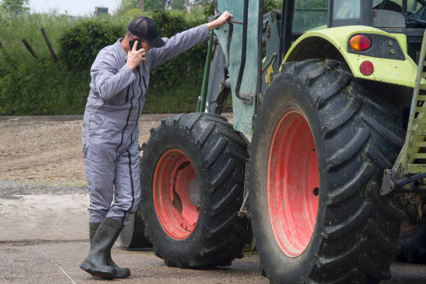 A farmer leans on his tractor and phone