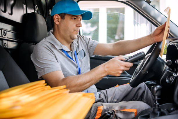 istock Man working in delivery service using scanner in vehicle interior 1496164979