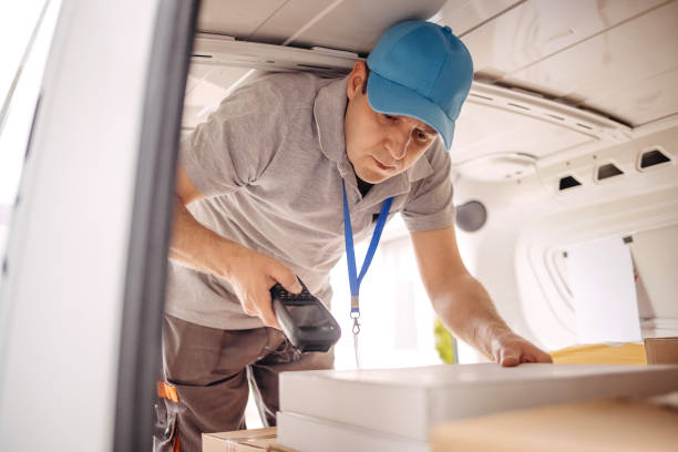 istock Man working in delivery service trying to find package to deliver using scanner 1496165812
