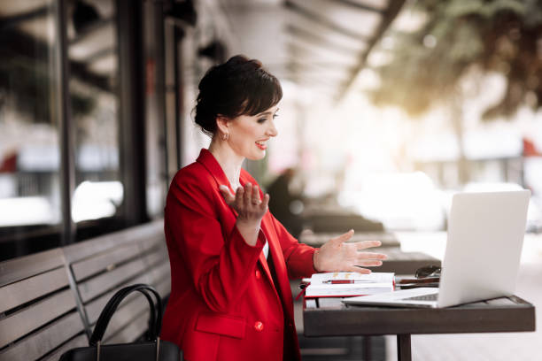 istock Young confident businesswoman using laptop computer working outdoors, having video call with clients or coworkers sitting at cafe terrace. Successful business. Online meeting, video conference concept 1496168356