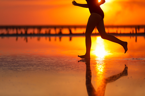 Active summer travel tropical holiday. Cropped silhouette of energy little child girls is having fun runs and plays on beach at sunset. Youth, lifestyle and happiness concept. Children's day.