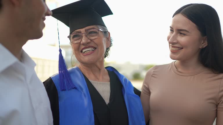 Senior graduate woman talking while embracing her daughter and son on her graduation