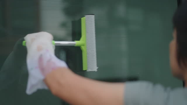 Woman cleaning window glass at home.