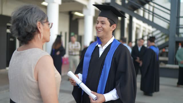 Young graduate man talking with his mother on the graduation