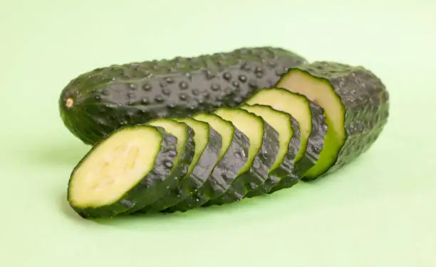 A fresh cucumber next to a sliced ​​cucumber
