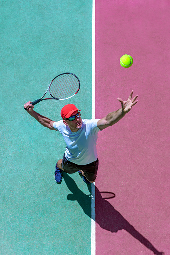 TENNIS PLAYER SERVING ON THE COURT PLAYING A TENNIS MATCH DURING A TOURNAMENT. OVERHEAD SHOT. TOP VIEW. SPORT BETS IN BETTING SHOPS.