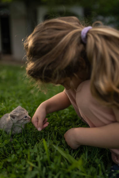 A latin girl sitting on the grass, holding a cat and smiling at the camera.