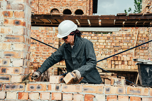 An experienced worker works on the construction of a brick house
