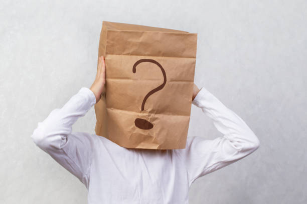 istock Anonymous man on a gray background with a cardboard box on his head with a drawn question mark. Problems and solutions. Getting answers. 1496174362