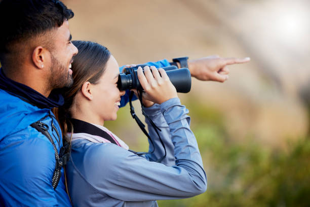 istock Binoculars, pointing and a couple bird watching in nature while hiking in the mountains together. Forest, nature or sightseeing with a man and woman looking at the view while bonding on a hike 1496176487