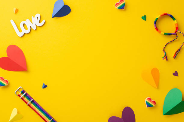 istock Parade symbolic accessories top view flat lay on a bright yellow background with a blank frame for text or advert, including wristlet, pin badges, hearts in rainbow colors 1496176536