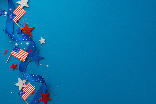 Top view festive decor, including serpentine, glitter stars, sparkle confetti, adorn blue backdrop with empty space for text or ad, creating a lively ambiance for an Independence Day USA celebration