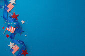 Top view festive decor, including serpentine, glitter stars, sparkle confetti, adorn blue backdrop with empty space for text or ad, creating a lively ambiance for an Independence Day USA celebration
