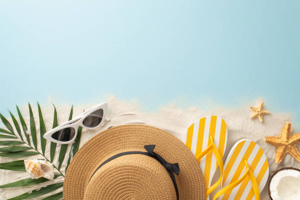 istock Summer beach holiday idea. Top view of vacation essentials: sunhat, flip-flops, shell, starfish, palm leaves, coconut. Empty space for text or ad on sandy and water backdrop 1496176593