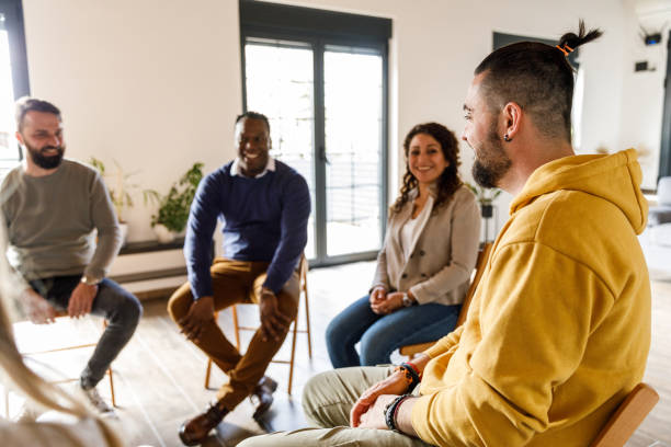 istock Group of people sitting in circle, talking during group therapy 1496177790