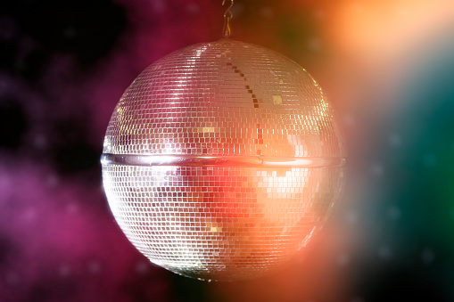 Disco ball with bright beams, night party background photo.