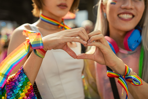 LGBTQ+ friends hands making heart shape in LGBTQ+ pride parade , Marriage equality