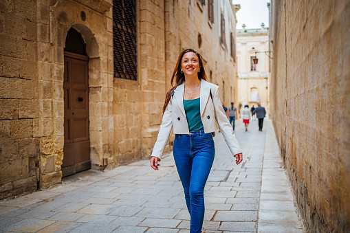 Young cheerful woman exploring and enjoying the view while walking in Mdina, Malta