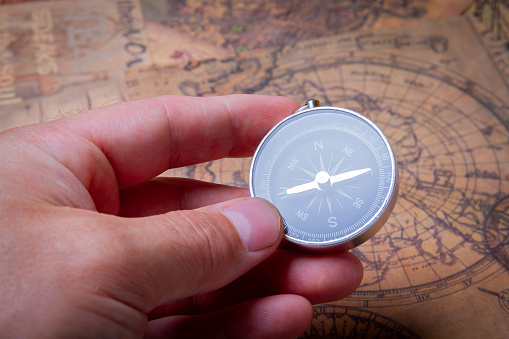 Adventure search. Compass and maps. Treasure hunt on island. Pirate map. Person holds compass in his hand.