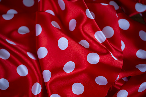Red silk fabric with large white polka dots. Polka dot background.