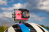 Action camera on a bicycle helmet against a blue sky background.