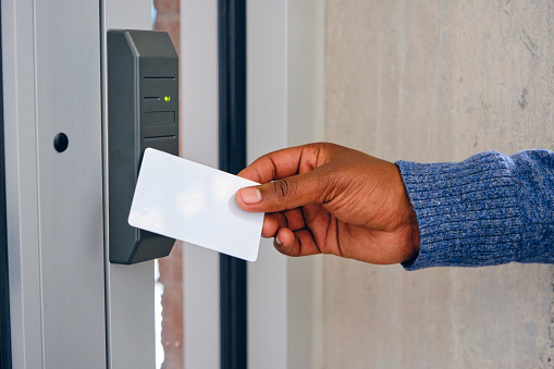 A hand using a key card to open an electronically locked door.