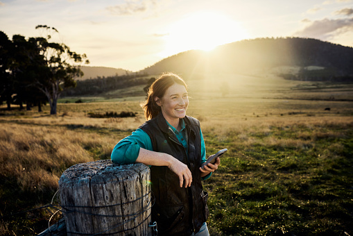 Young female farmer staying in touch via mobile technology from her farm in rural Tasmania, Australia.